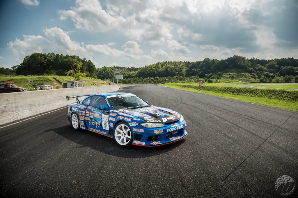 WORK EMOTION T7Rのホワイトホイールを装着したブルーのドリフト競技車両とサーキット風景