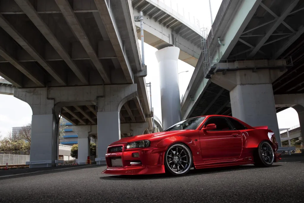 高架下に停車するZR10ホイール装着の赤い日産スカイラインR34