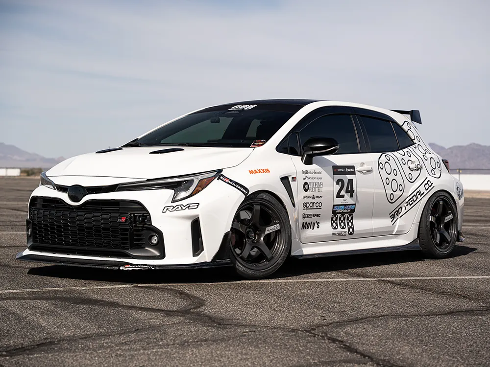 レーシングデカールを施した白いGRカローラを前方斜めから撮影。黒いR50 EVOホイールとフロントバンパーが見える