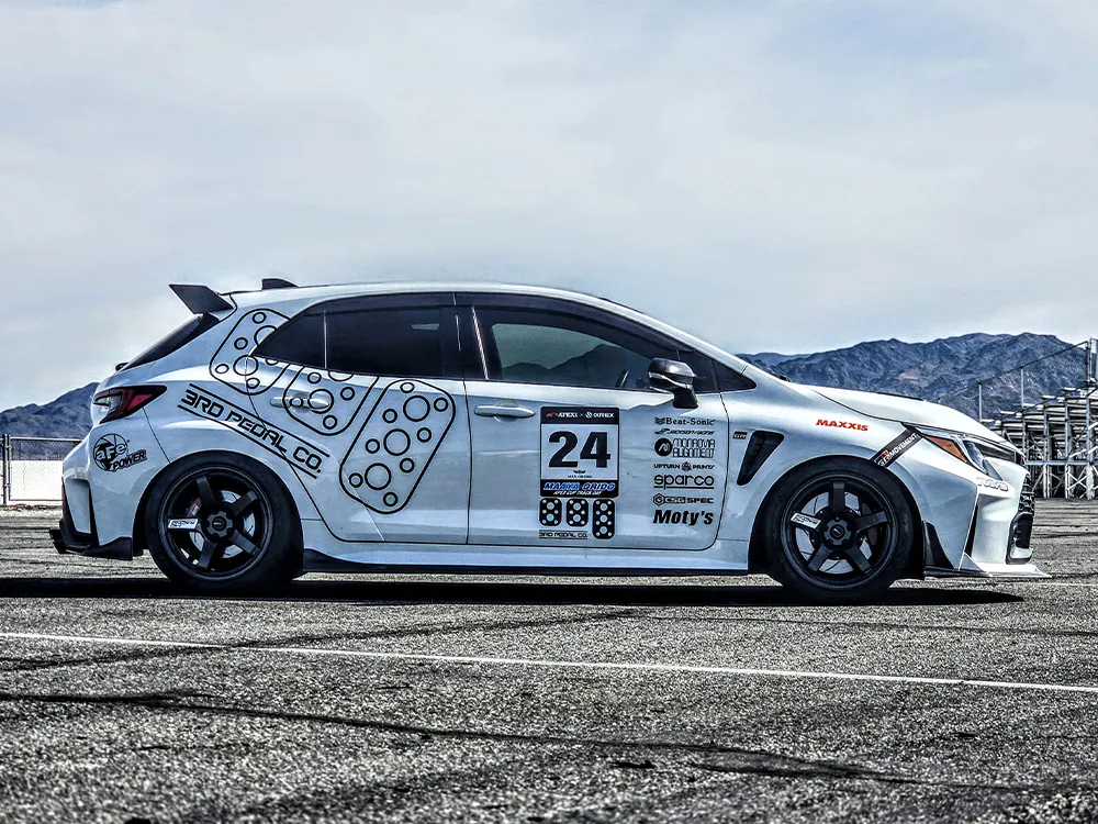 ゼッケン24を付けた白いGRカローラの側面。前後の黒いR50 EVOホイールとレーシングデカールが見える