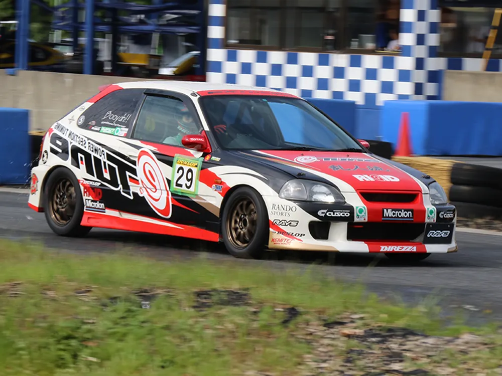 サーキットを走行するゼッケン29の赤・白・黒のホンダ・シビック競技車両。ブロンズ系ホイールが見える