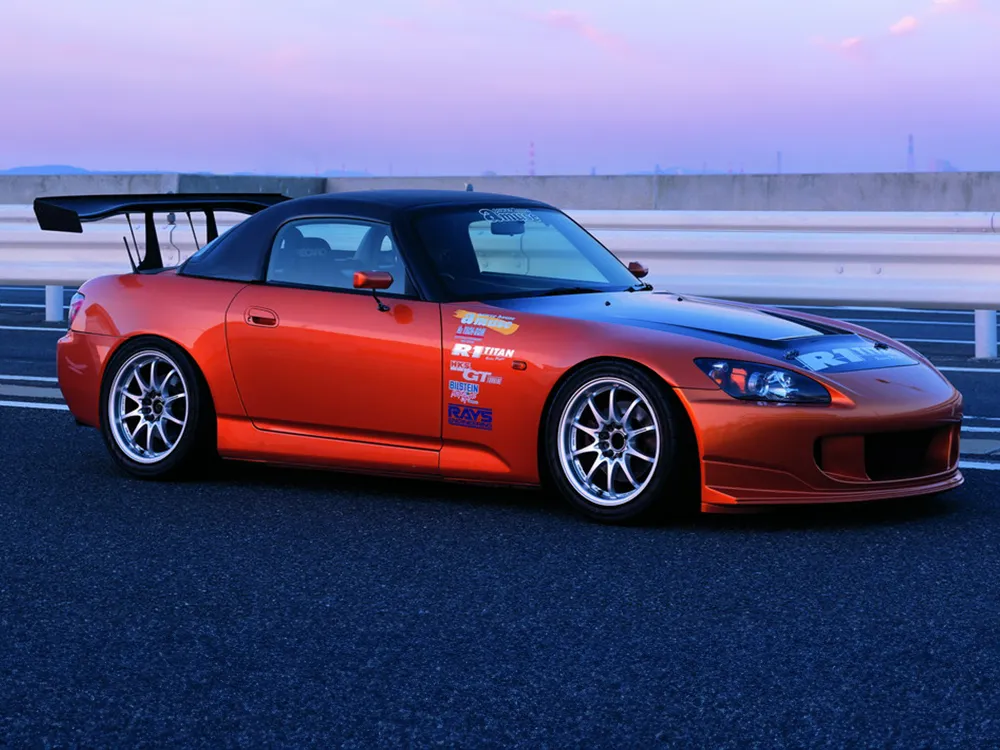 大型リアウイングとシルバー系ホイールを備えたオレンジ色のホンダS2000を斜め横から撮影