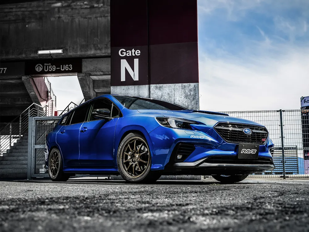 ブロンズ系ホイールを装着した青いスバルWRX STIを前方斜めから撮影