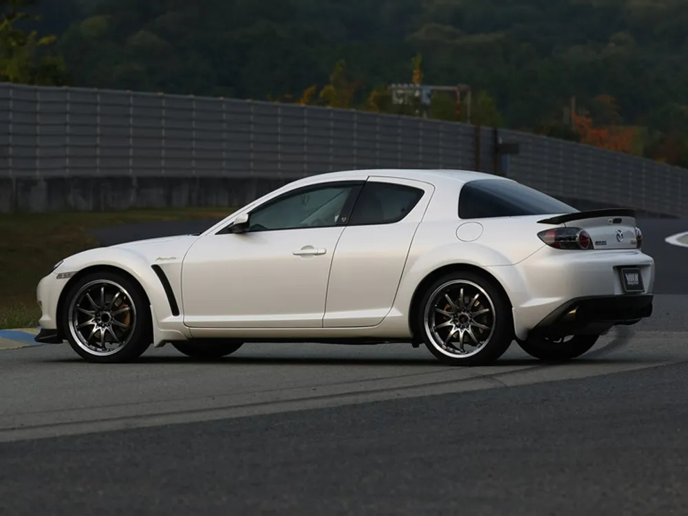 サーキット上で横から撮影した白いマツダRX-8。ダーク系の細身スポークホイールを装着