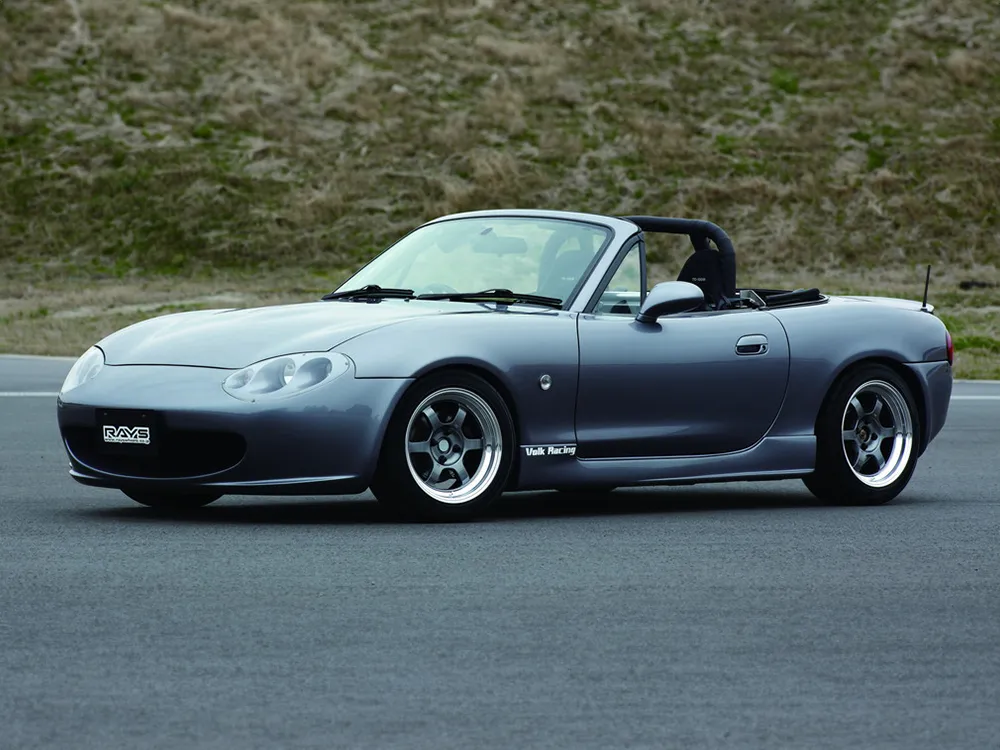 グレーブルーのマツダ・ロードスターNB型に深リムの6本スポークホイールを装着したオープン状態の側面写真