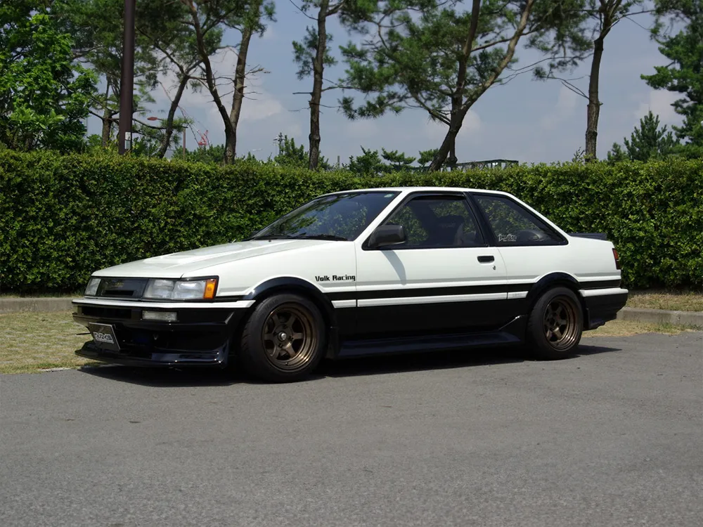 白黒ツートンのトヨタ・カローラレビンAE86にブロンズの6本スポークホイールを装着した側面写真
